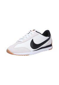 Zapatilla deportiva blanca y gris con acentos negros, material de gamuza y tela, puntera redonda, cierre de cordones y suela de goma con detalles en color marrón.