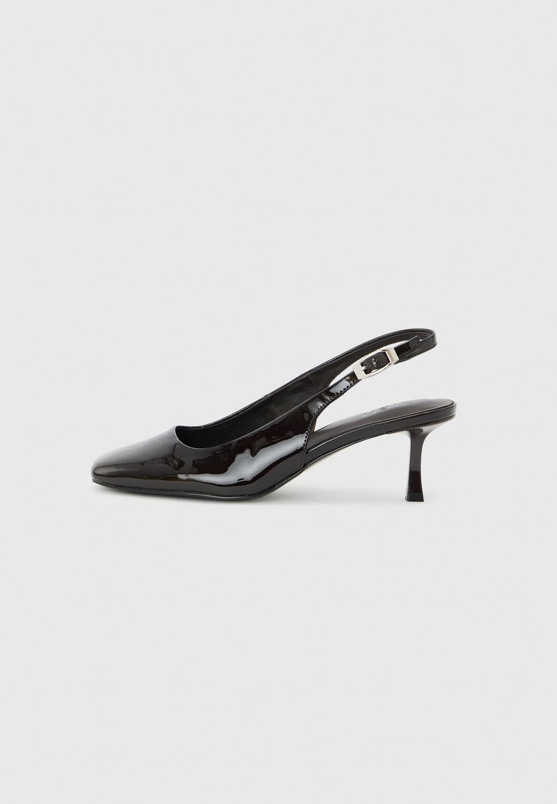 Μαύρο δερμάτινο παπούτσι slingback με μυτερή μύτη, ασημί αγκράφα και μεσαίο τακούνι kitten σε απλό φωτεινό φόντο.