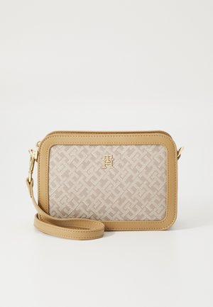 Beżowa i brązowa torebka na nadgarstek z geometrycznym wzorem, złotym logo oraz odpinanym paskiem na białym tle.