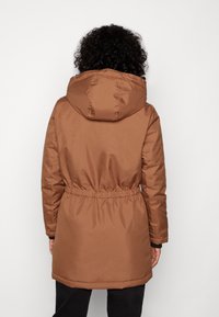 Brun isoleret parka med aftagelig hætte, elastisk talje og lommer. Glat tekstur med en let skinnende finish.