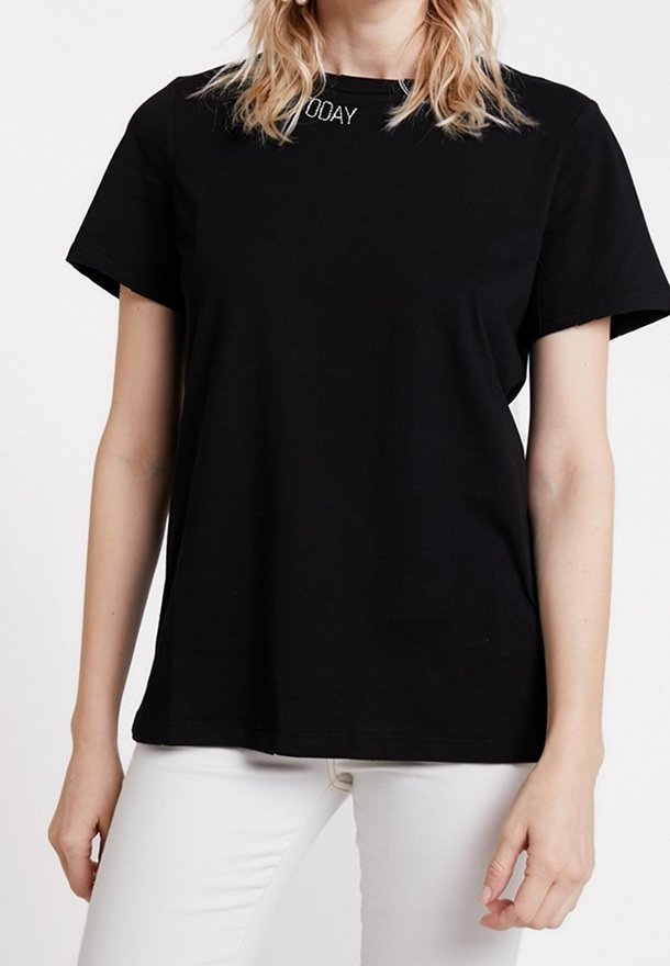 Black short-sleeve T-shirt made of cotton, featuring a round neckline and white "TODAY" embroidery at the collar. Worn with white pants.