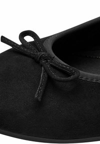 Melnā zamšā izgatavoti baleta kurpes ar noapaļotu purngali, elastīgu apdari un dekoratīvu loku ar saskaņotu šuvju detalizāciju.