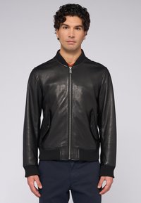 Černá kožená bomber bunda s žebrovaným límcem a manžetami, s bočními kapsami a zipem. Hladká textura s minimálním zdobením.