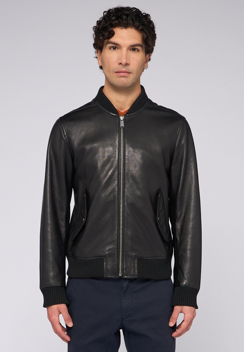 Černá kožená bomber bunda s žebrovaným límcem a manžetami, s bočními kapsami a zipem. Hladká textura s minimálním zdobením.