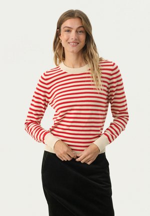 Röd och krämrandig tröja, rund halsringning, ribbade ärmslut och nederkant. Bärs med en svart kordkjol, med strukturerad tyg.