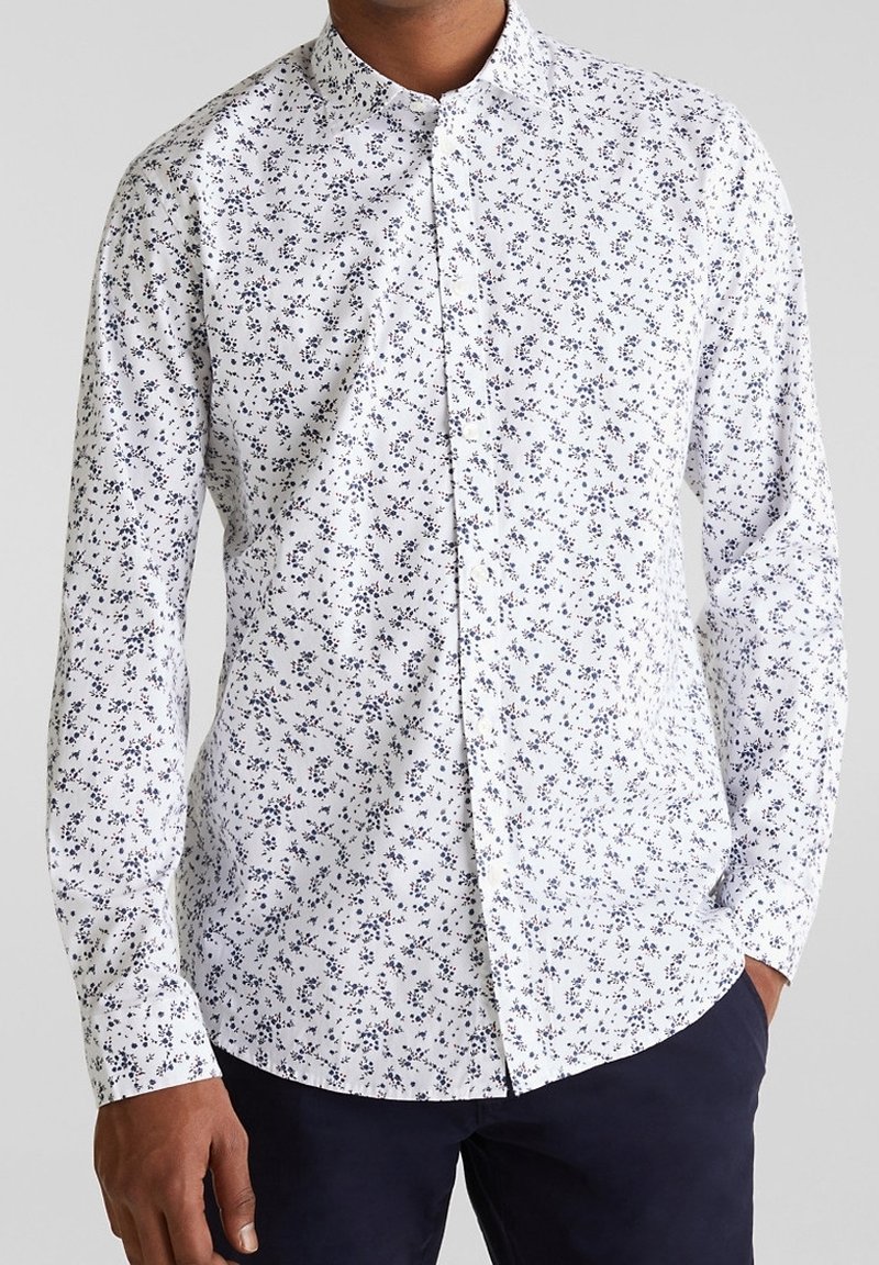 Chemise blanche à boutons avec un petit motif floral bleu marine, manches longues et col pointu. Tissu lisse avec une coupe classique.