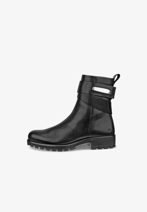 Botte cheville en cuir noir avec un bout rond, semelle en caoutchouc texturée, sangle décorative et un accent métallique près de la cheville.