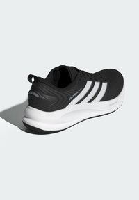 Black athletic shoe with a textured upper, three white stripes on the side, and a contrasting white midsole. Lightweight design with a rear pull tab.