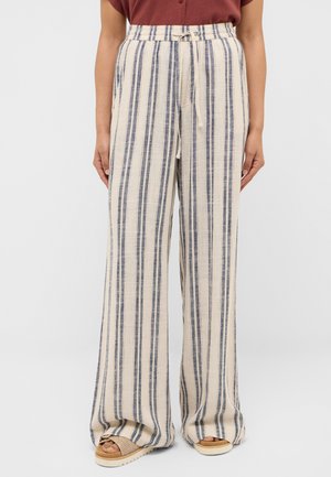 Wide-leg beige pants with vertical black stripes, drawstring waist, worn with tan sandals and a maroon top.
