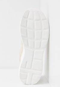 Semelle de chaussure de sport, dotée d'un design en caoutchouc blanc texturé avec un motif en grille et des bords arrondis, montrant des matériaux supérieurs beiges clairs et roses.