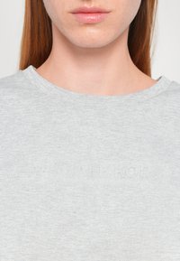 Gray cotton t-shirt featuring a round neckline and embossed "Michael Kors" logo near the hem. Smooth texture with a light, breathable feel.