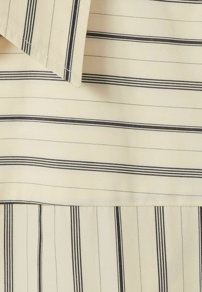 Tessuto beige chiaro con righe verticali nere. Presenta un colletto piatto e un design plissettato. Texture liscia con cuciture uniformi.