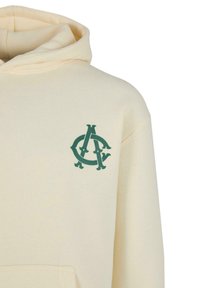 Kremowa bluza z kapturem wykonana z miękkiego materiału, z przednią kieszenią, z ciemnozielonym logo na lewej części klatki piersiowej.