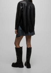 Black leather boots with a chunky sole, extending to mid-calf. The heel is thick with a loop for easy wear, displayed against a neutral background.