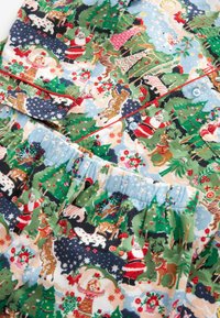 Pajama set s barevným vánočním potiskem se Santou, soby a stromy. Bavlněná látka, zapínání na knoflík a elastický pas.