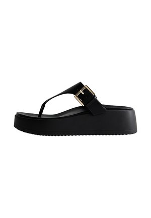 Sandalia tipo flip-flop negra con suela gruesa, tira tipo tanga y hebilla grande dorada en el lateral.