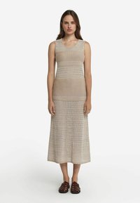 Stickad midiklänning i beige, med ribbad textur och öppen väv samt rund halsringning. Matchad med bruna remsandaler.