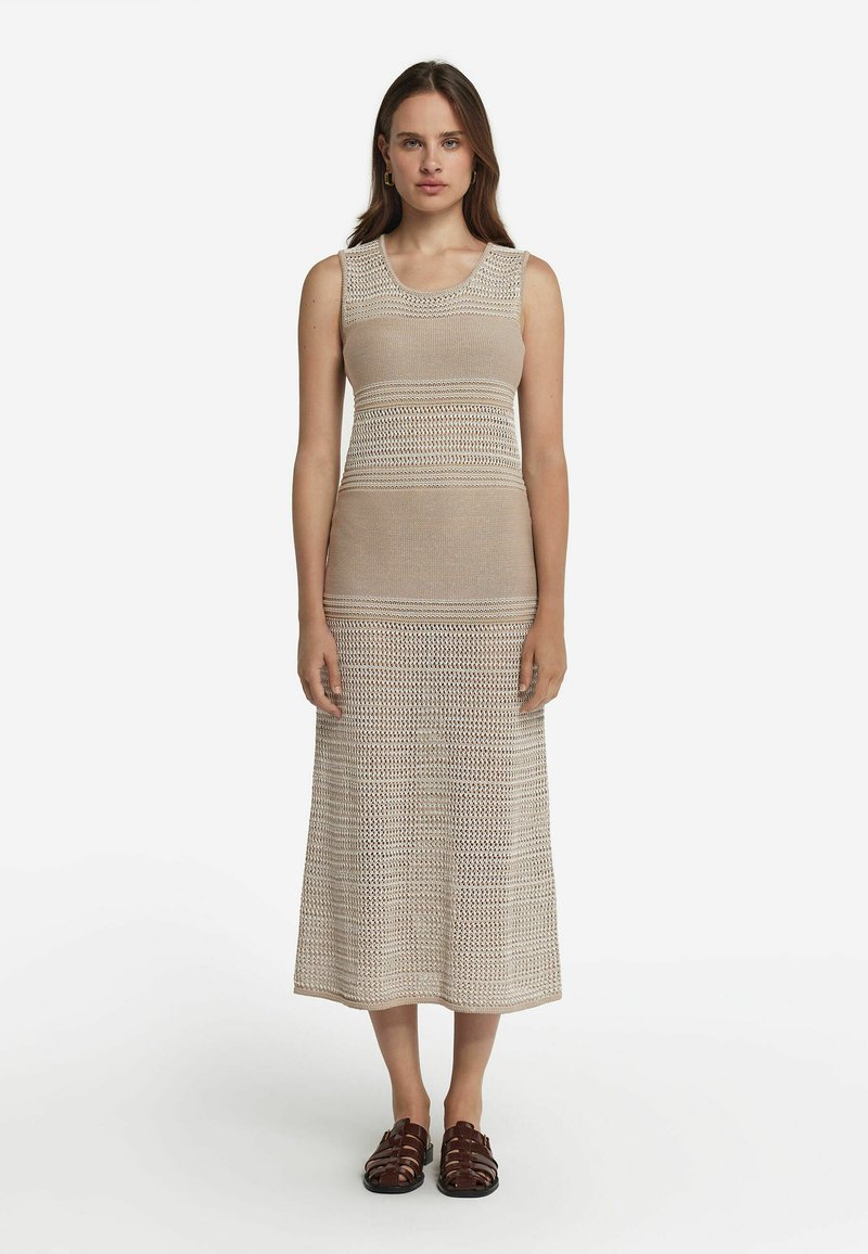 Stickad midiklänning i beige, med ribbad textur och öppen väv samt rund halsringning. Matchad med bruna remsandaler.