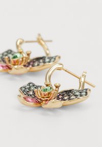Gold-colored earrings designed as flowers, featuring green and pink gemstones, textured petals, and a hoop fastening.