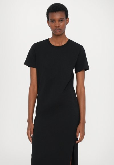 Rochie din bumbac neagră, cu mânecă scurtă, dintr-un material neted și elastic, cu o fanta pe lateral. Design simplu și decolteu rotund.