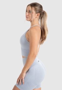 Conjunto de ropa deportiva azul claro que incluye un top corto ajustado con tirantes finos y pantalones cortos de tiro alto, fabricado con un tejido suave y elástico.