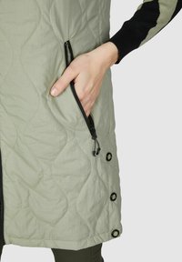 Gepolsterte Jacke in hellgrün mit schwarzem Reißverschluss und Taschen. Besitzt ein strukturiertes Muster und schwarze Strickakzente an den Ärmeln.