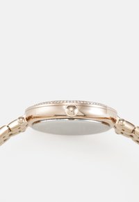 Reloj de oro rosa con cara redonda, bisel adornado y pulsera de eslabones de metal; presenta una pequeña corona y un acabado suave y brillante.