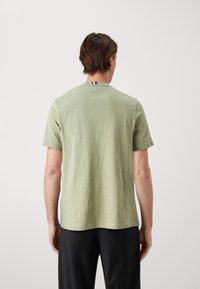 Lys grøn t-shirt med korte ærmer, rund hals og en subtil tekstur. Har en stribet detalje bag på halsen.