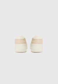 Beige plattform sneakers med glatt skinn og teksturerte tøyakenter. Tykk hvit gummisåle og avrundete hæler. Enkel design, ingen dekorasjoner.