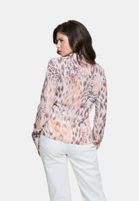 Blusa a maniche lunghe in tessuto leggero e stampato con una combinazione di stampe animali in rosa pallido e marrone. Leggermente sagomata, con colletto e polsini abbottonati.