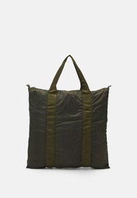 Sac fourre-tout rembourré vert avec deux poignées en tissu. Il dispose d'une fermeture éclair et d'une texture lisse, adapté au transport ou au rangement.