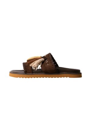 Sandale mule en daim marron avec deux pampilles décoratives beige et marron clair sur la bride et une semelle en caoutchouc marron clair aux bords ondulés.