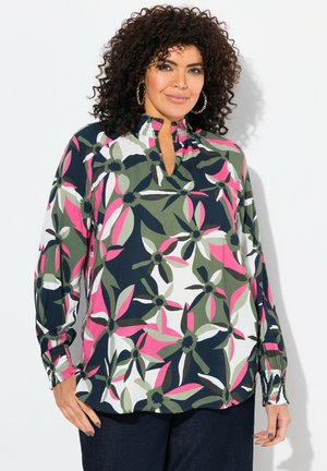 Blusa a maniche lunghe di colore blu navy con un motivo floreale nei toni del rosa, verde e bianco. Presenta un'apertura a chiave sul collo e polsini arricciati. Tessuto leggero.