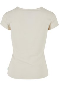 Krämefärgad, figurnära t-shirt med korta ärmar och rundad halsringning. Slät yta, inga mönster och en liten grön märkesflik på sidan.