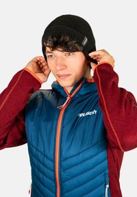 Black ribbed beanie and a blue puffer jacket with red sleeves and orange accents, featuring a zip closure and logo on the chest.