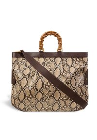 Sac fourre-tout en simili cuir serpent beige avec des accents en cuir brun foncé et une poignée en bambou ; comprend une longue sangle pour un port en bandoulière.