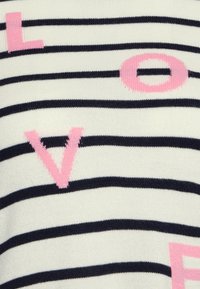 Sweter dzianinowy w paski w kolorze kremowym z granatowymi poziomymi pasami. Posiada duże różowe litery, które tworzą napis "LOVE", podkreślające fakturę i design.