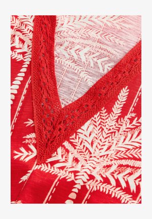 Tissu rouge avec un motif de fougère en blanc, présentant un décolleté en V ourlé de dentelle. La texture est lisse avec une apparence légèrement transparente.