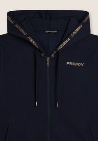 Felpa con zip di colore navy con logo dorato e cordini. Presenta una texture morbida e un cappuccio foderato con dettagli brandizzati.