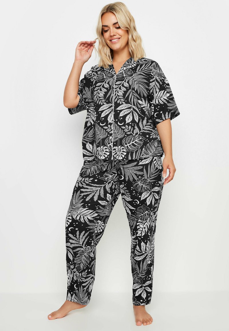 Svart och vit pyjamas med ett blommigt bladmönster, kortärmad knäpptröja och löst sittande byxor med elastisk midja.