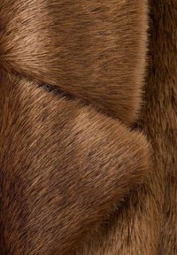 Tessuto in pelliccia sintetica marrone, caratterizzato da una texture liscia con lunghezze e profondità variabili, che crea un aspetto stratificato in tonalità calde e terrose.