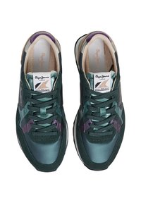 Zapatillas deportivas verdes con una mezcla de materiales lisos y texturizados, con acentos morados, cordones redondos y un cuello acolchado para mayor comodidad.