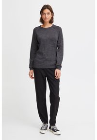 Dark gray textured sweater with a crew neckline and raglan sleeves, paired with relaxed black pants and classic black sneakers.