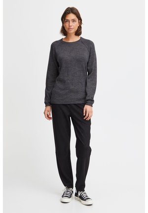 Pull en maille texturée gris foncé avec un col rond et des manches raglan, associé à un pantalon noir décontracté et des baskets noires classiques.