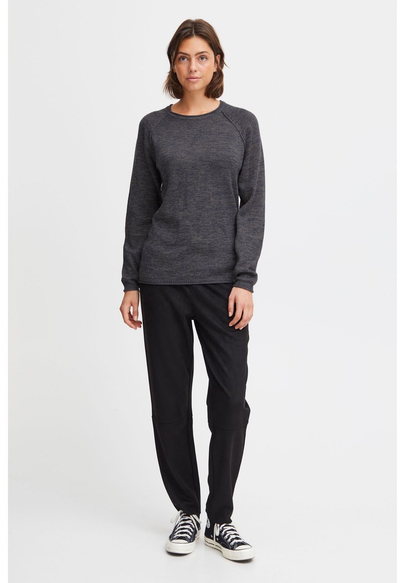 Dark gray textured sweater with a crew neckline and raglan sleeves, paired with relaxed black pants and classic black sneakers.