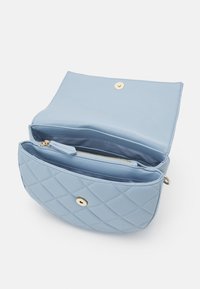 Ljusblå quiltad handväska med en slät yta, utrustad med ett guldfärgat tryckknappslås och en innerficka med dragkedja för organisering.