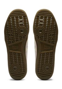 Tan rubber shoe soles with a textured grip pattern, rounded accents, and a central logo reading "Onitsuka Tiger."