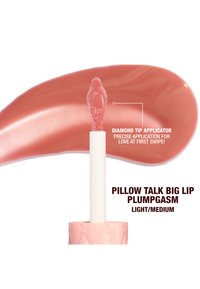 Lippenbalsam in hellpink mit einem Applikator mit Diamantspitze, der ein glattes, glänzendes Finish auf einem Farbmuster in passender Farbe präsentiert.