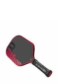 Paddle da pickleball Wilson con superficie nera, perimetro rosso e impugnatura nera testurizzata. La testa ha una forma arrotondata con una finitura liscia.