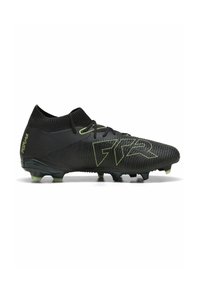 Bota de fútbol negra con una superficie texturada, cuenta con un collarín ajustado para el tobillo, acentos verdes y una suela con múltiples tacos para tracción.
